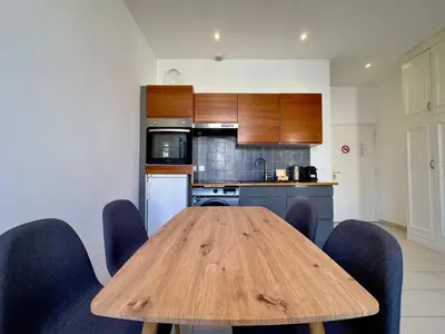 a kitchen with a wooden table and blue chairs at Andréa By SCLS Locations in Cannes
