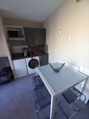 a kitchen with a white table and a microwave at appartement les pieds dans l'eau in Cannes