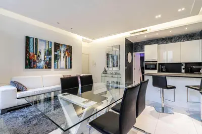 a living room with a glass table and a kitchen at Large renovated studio - rue Hoche - Cannes center in Cannes