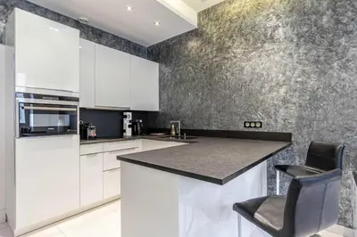a kitchen with white cabinets and a black counter top at Large renovated studio - rue Hoche - Cannes center in Cannes