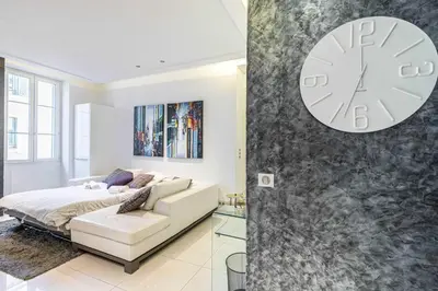 a bedroom with a bed and a clock on a wall at Large renovated studio - rue Hoche - Cannes center in Cannes