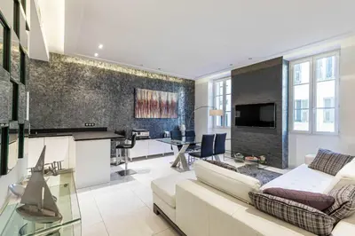 a living room with a white couch and a fireplace at Large renovated studio - rue Hoche - Cannes center in Cannes