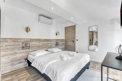 a white bedroom with two beds and a table at 2 Chambre L - Ascenseur - Proche palais - Calme in Cannes