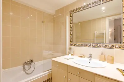 a bathroom with a sink and a tub and a mirror at Super Californie YourHostHelper in Cannes