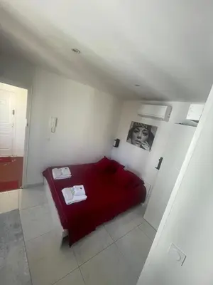 a bedroom with a red bed in a white room at Sweet Home Marceau - 6 studios hyper centre proche de la mer et du palais in Cannes