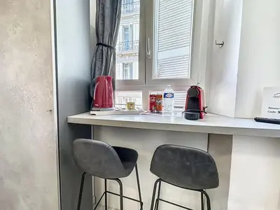 a kitchen with two stools at a counter with a window at Sweet Home Marceau - 6 studios hyper centre proche de la mer et du palais in Cannes