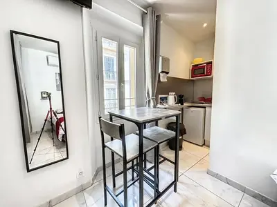 a small kitchen with a table and a mirror at Sweet Home Marceau - 6 studios hyper centre proche de la mer et du palais in Cannes