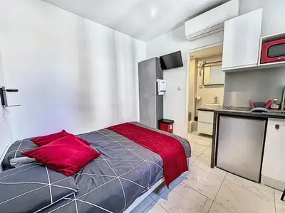 a bedroom with a bed with a red pillow on it at Sweet Home Marceau - 6 studios hyper centre proche de la mer et du palais in Cannes
