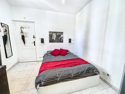 a white bedroom with a bed with red pillows at Sweet Home Marceau - 6 studios hyper centre proche de la mer et du palais in Cannes
