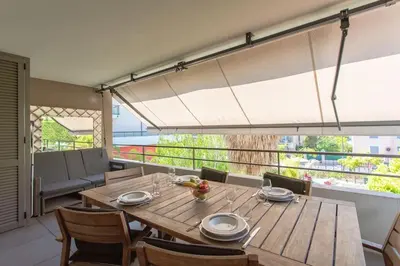 a dining room with a wooden table and a large window at C2 - 2 BDR Montfleury - Pool, Garage, Terrace & AC in Cannes