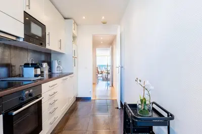 a kitchen with white cabinets and a black stove at PANORAMIC SEA VIEW - 2-Br Apartment Mouré Rouge in Cannes