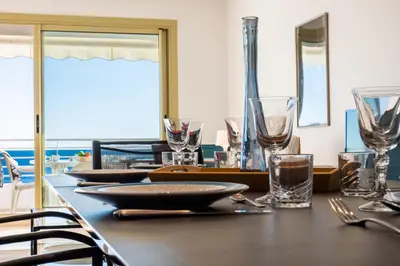 a table with glasses and plates on top of it at PANORAMIC SEA VIEW - 2-Br Apartment Mouré Rouge in Cannes