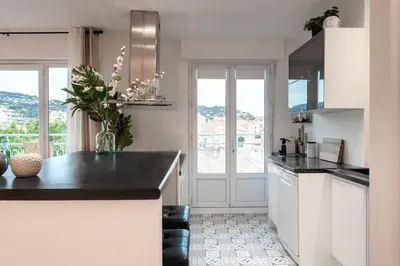a kitchen with white cabinets and a black counter top at C5 - 2 BDR Blvd Carnot - 10 min Palais - AC & Terrace Sea View in Cannes