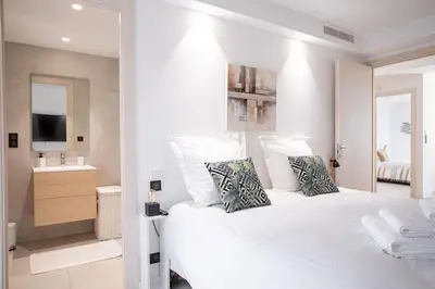 a white bedroom with a large white bed and a bathroom at Amazing Apartment With Private Terrace & Full Air Conditioning - Walk To The Beach, La Croisette! - Latour Maubourg 18 by Halldis in Cannes