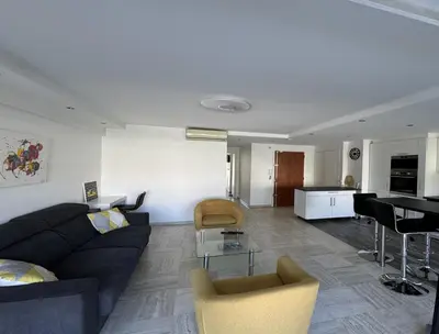 a living room with a black couch and a table at Charming 2 room , 52 m2, very spacious, bright and near sea Martinez hotel in Cannes