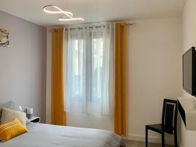 a bedroom with a bed and a window with orange curtains at Foras Urban Living à 2 pas du festival in Cannes