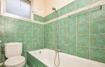 a green tiled bathroom with a toilet and a tub at Beautiful Apartment In Cannes With Wifi in Cannes