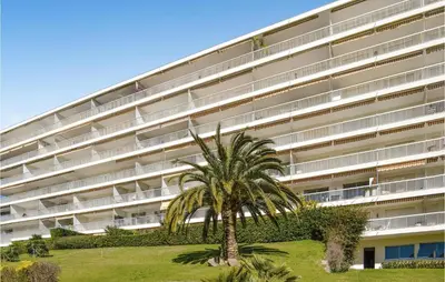 a palm tree in front of a large building at Beautiful Apartment In Cannes With Wifi in Cannes