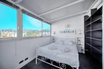 a white bedroom with a bed and a large window at IMMOGROOM -Rooftop 150m2 -Terrace 150m2 -Parking -Wifi - AC in Cannes