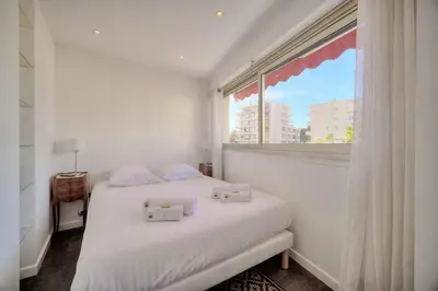 a bedroom with a white bed with a large window at IMMOGROOM -Rooftop 150m2 -Terrace 150m2 -Parking -Wifi - AC in Cannes