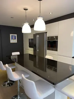 a kitchen with a black counter and white chairs at Magnifique Modern appartement avec terrasse FERN12 in Cannes