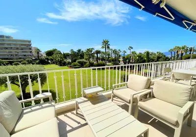 a balcony with white chairs and a table and a view at Viva Riviera Résidence Les Dunes 90 Croisette in Cannes