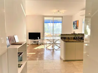 a kitchen with a counter and a living room at Viva Riviera Résidence Les Dunes 90 Croisette in Cannes