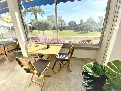 a table and chairs in a room with a large window at Viva Riviera Résidence Les Dunes 90 Croisette in Cannes