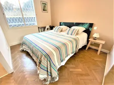 a bedroom with a bed with a striped blanket and a window at Viva Riviera Résidence Les Dunes 90 Croisette in Cannes