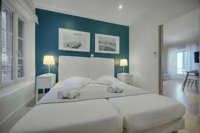 a bedroom with a large white bed with blue walls at IMMOGROOM- Apartment 70m2 - Renovated - Wifi - AC - Close to everything in Cannes
