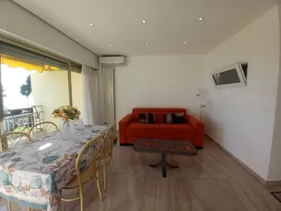 a living room with a table and a red couch at Le Trident B in Cannes