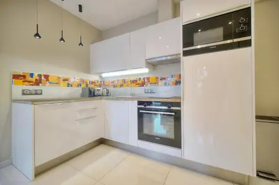 a white kitchen with white cabinets and appliances at Elégant 2 pièces TERRASSE, CARLTON MARTINEZ- Proche CROISETTE A1B238 in Cannes