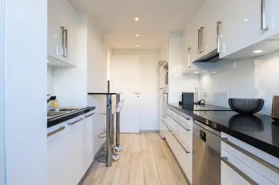 a kitchen with white cabinets and black counter tops at 2-Br in high Residential Property in Cannes