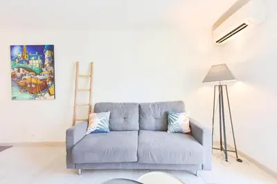 a blue couch in a living room with a painting at 1-Br apartment in the heart of Cannes in Cannes