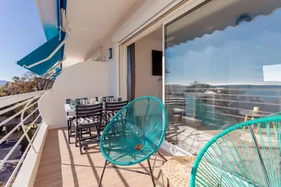 a balcony with chairs and tables and a view of the ocean at Apartment With Panoramic Sea View, Walk To The Beach - Maréchal Juin by Halldis in Cannes