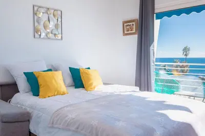 a bedroom with a bed with yellow and blue pillows at Apartment With Panoramic Sea View, Walk To The Beach - Maréchal Juin by Halldis in Cannes