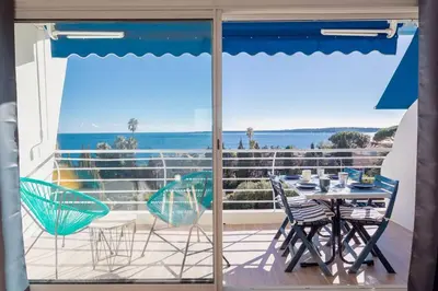 a balcony with a table and chairs and a view of the ocean at Apartment With Panoramic Sea View, Walk To The Beach - Maréchal Juin by Halldis in Cannes
