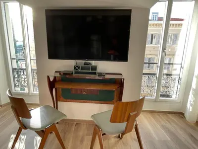 a living room with two chairs and a flat screen tv at FELIX FAURE PALAIS DES FESTIVALS CROISETTE VIEUX PORT in Cannes