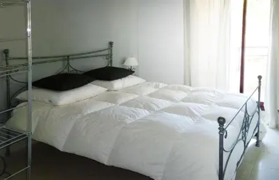 a bed with white sheets and black pillows in a bedroom at VILLAS DES LYS in Cannes
