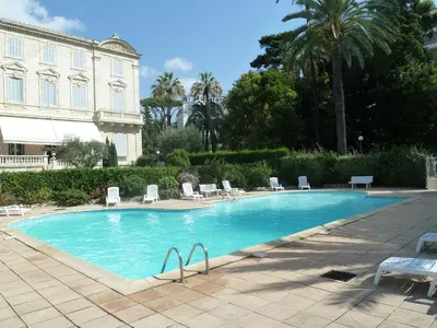 a large swimming pool with chairs and a building at VILLAS DES LYS in Cannes
