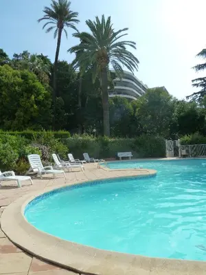 a large swimming pool with chairs and palm trees at VILLAS DES LYS in Cannes