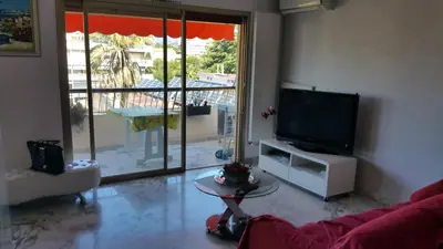 a living room with a couch and a tv and a balcony at Moderne Appartement Cannes Californie in Cannes