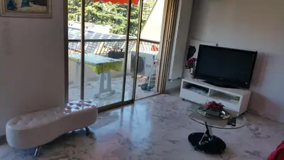 a living room with a tv and a chair and a table at Moderne Appartement Cannes Californie in Cannes