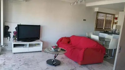 a living room with a red couch and a tv at Moderne Appartement Cannes Californie in Cannes