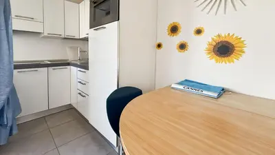 a kitchen with a wooden table with sunflowers on the wall at Modern 2 Bd Next To Rue Dantibes in Cannes