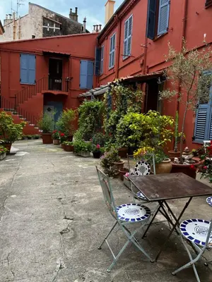 a table and chairs in front of a red building at Joli Studio sur le Port in Cannes