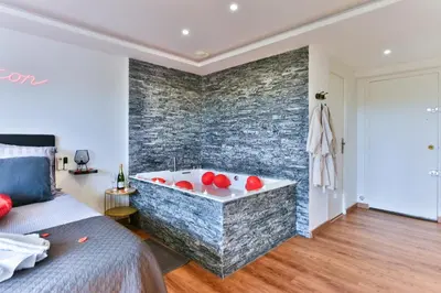 a bath tub in a room with a brick wall at LE COCON- Jacuzzi & Sauna privés By SweetDreams in Le Cannet