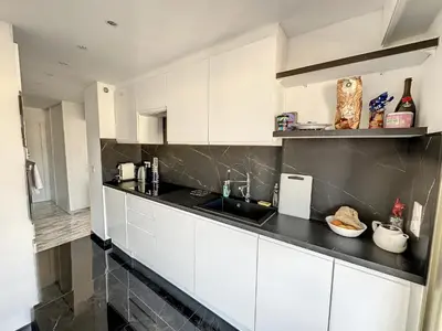 a kitchen with white cabinets and a black counter top at SUQ3 - Très beau 2 pièces avec terrasse in Cannes