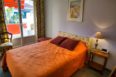 a bedroom with a bed with an orange blanket and a window at Ref JUAS - Palmes d'Or Properties in Cannes