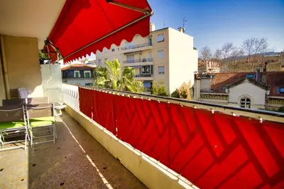 a red wall on top of a balcony with chairs at Ref JUAS - Palmes d'Or Properties in Cannes